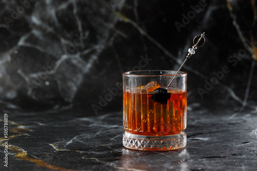 Obraz na płótnie Old fashioned cocktail, consisting of Bourbon, Angostura Bitter, sugar cubes, a few drops of water, ice cubes, orange, maraschino cherry w salonie