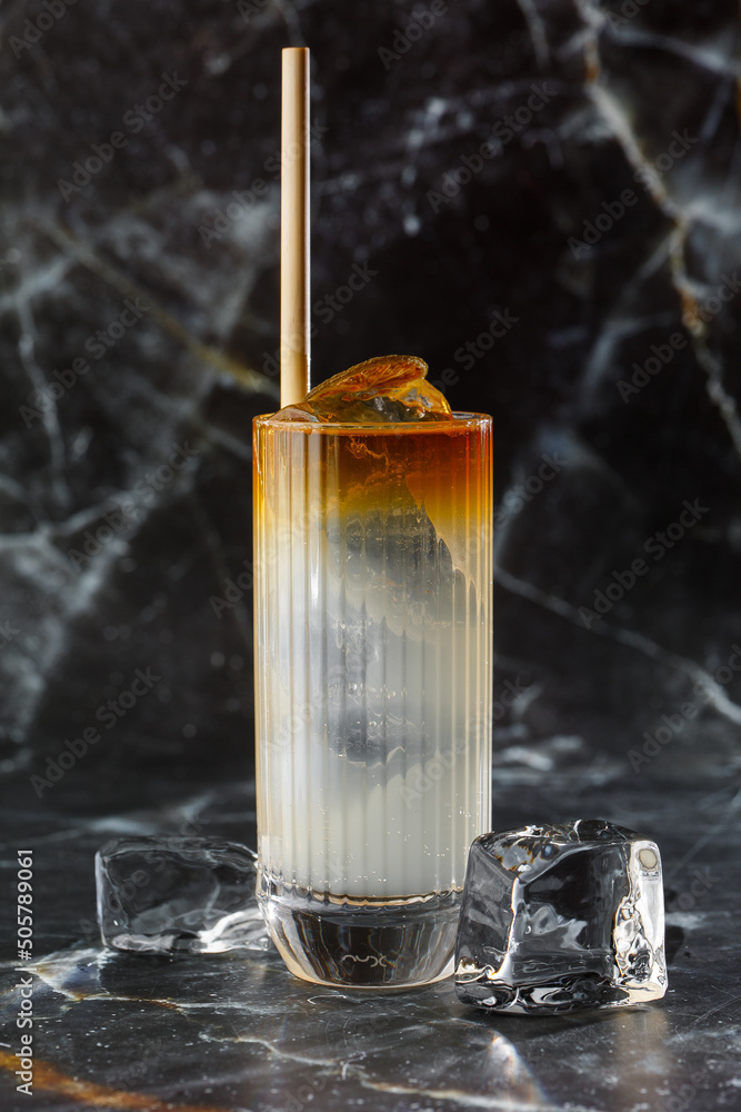 Dark n Stormy cocktail standing on the black marble background. Refreshing Boozy Rum Dark and Stormy Cocktail with Ginger Beer.