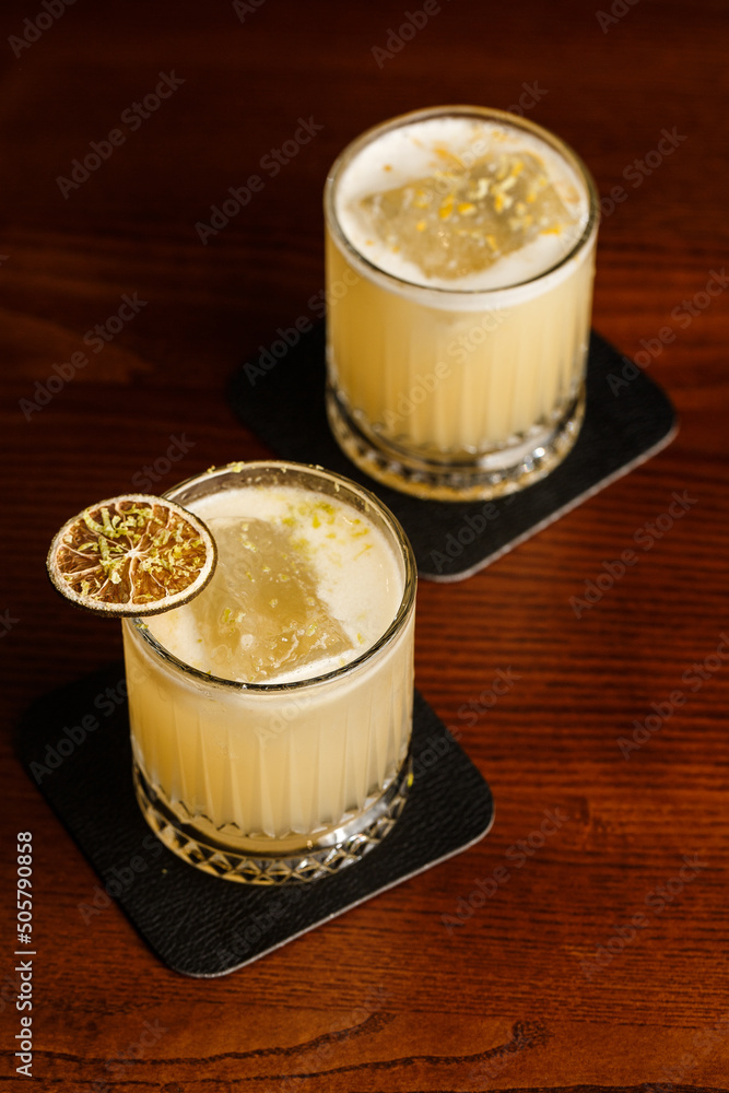 Warm colored cocktails. Mezcal cocktail and Alcoholic Scotch Whiskey Penicillin Drink Cocktail. Cocktail glass on bar counter