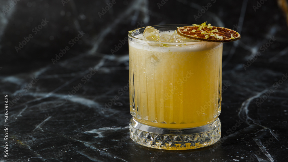 Fruit mixology with mezcal and dry lime on black marble background. Warm colored cocktails. Mezcal cocktail.
