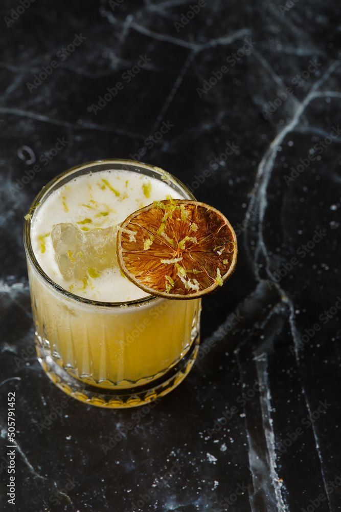 Fruit mixology with mezcal and dry lime on black marble background. Warm colored cocktails. Mezcal cocktail.