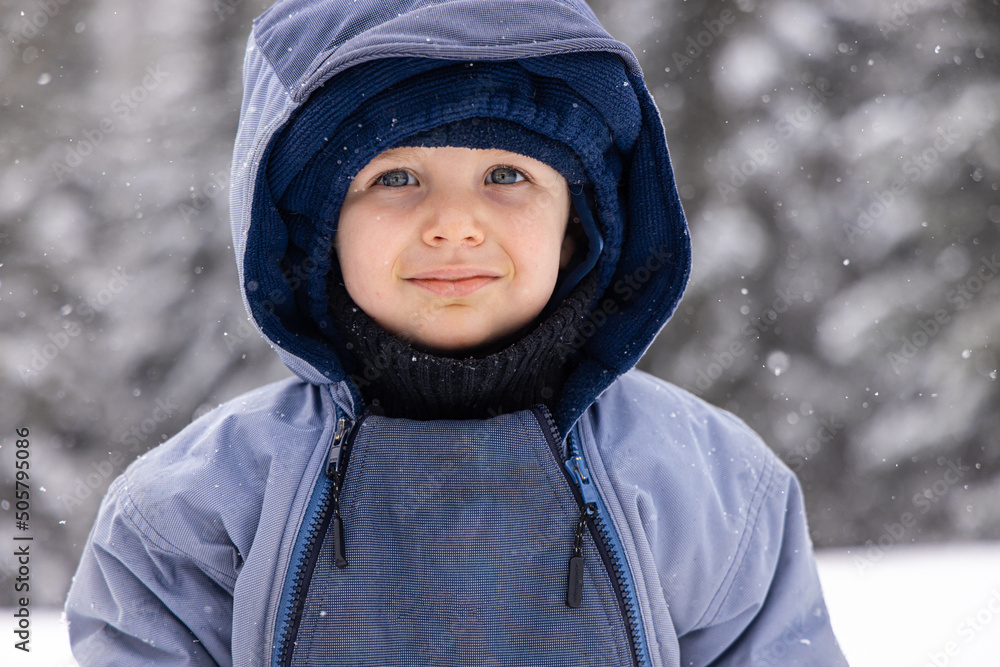 Close up headshot of a cute healthy 2 year old boy, wrapped up warm and standing in the countryside during winter with snowy trees in background. Close up headshot of a cute healthy 2 year old boy, wrapped up warm and standing in the countryside during winter with snowy trees in background.
