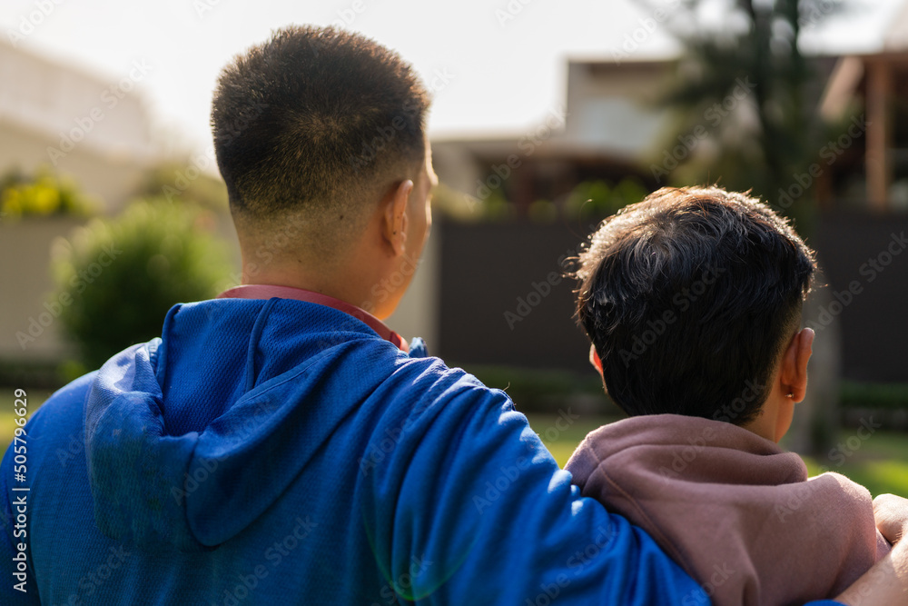 Gay couple embraced while facing some residential buildings from a park Gay couple embraced while facing some residential buildings from a park