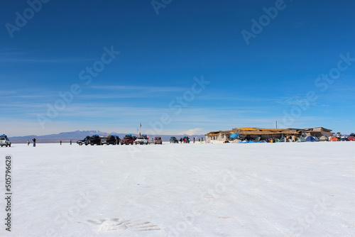 Salar de Uyuni, carros de transporte de turistas estacionados no horizonte branco .