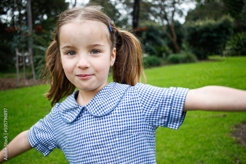 Close up shot of a school girl in uniform playing outside with her arms out