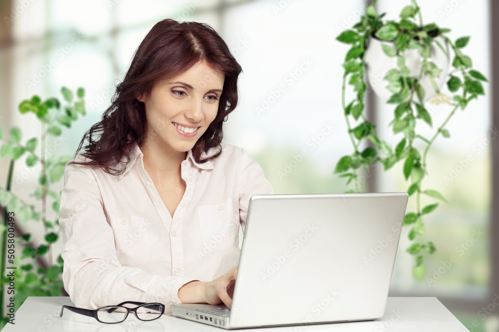 Happy office manager working on laptop in office building. Happy office manager working on laptop in office building.
