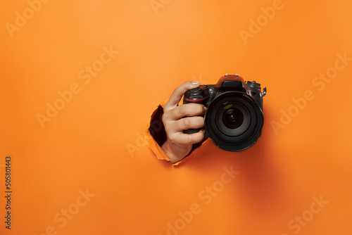mano sosteniendo una camara fotografica con comcepto de roper el papel de fondo ycon espacio para copy