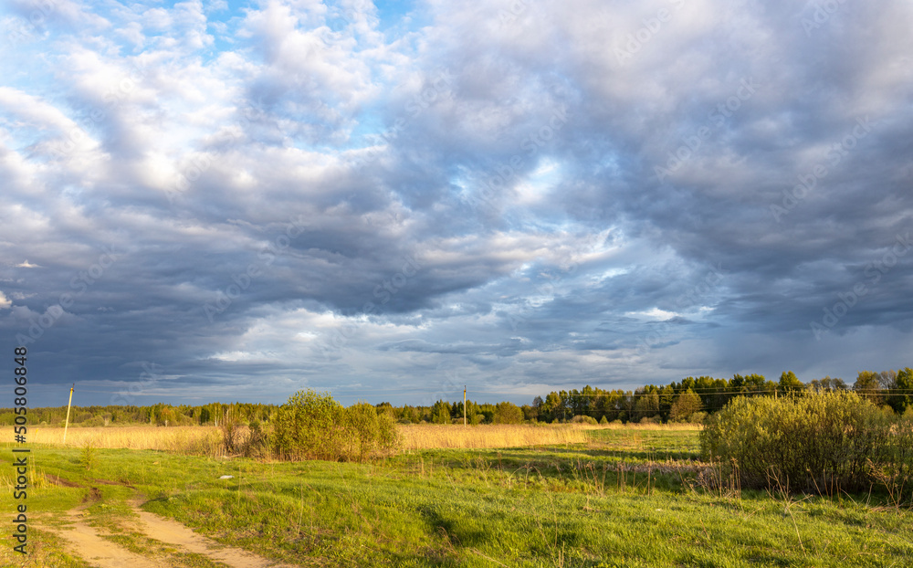 Spring landscape with dramatic sky and vibrant greenery illuminated by sunlight Spring landscape with dramatic sky and vibrant greenery illuminated by sunlight