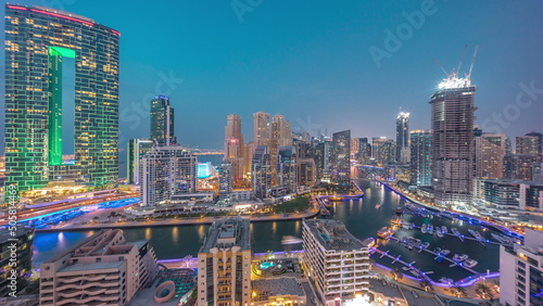 Panorama of Dubai Marina with several boat and yachts parked in harbor and skyscrapers around canal aerial day to night timelapse.