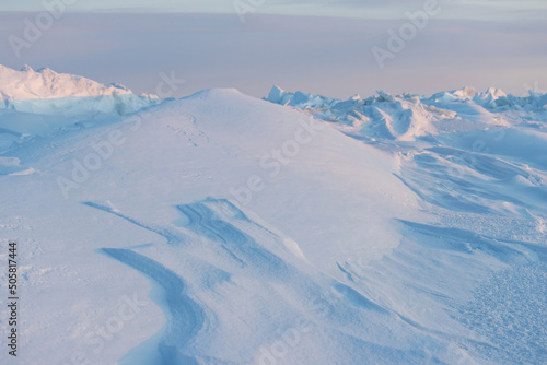 Winter arctic landscape. View of snow and ice at sunset. Ice hummocks on the frozen sea in the Arctic. Cold frosty winter weather. Harsh polar climate. Travel and hikes to the far north to the Arctic. photo