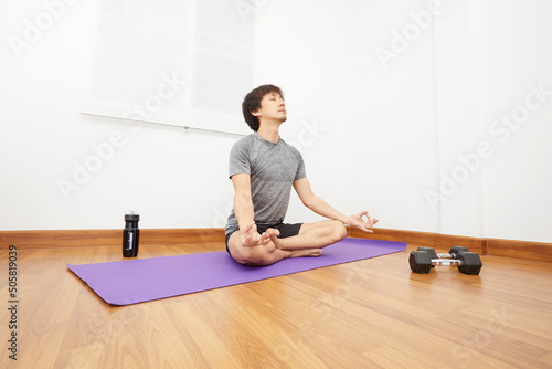 Exercises at home concept, Asian man practicing yoga on the yoga mats at home.