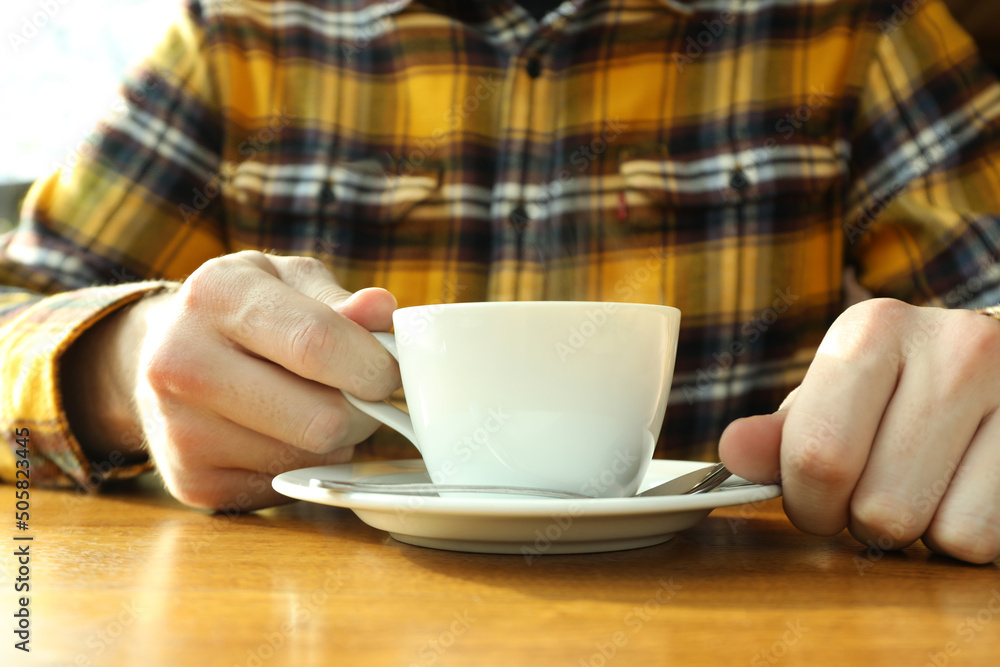 Young man sitting on table in restaurant and drinking coffee Young man sitting on table in restaurant and drinking coffee