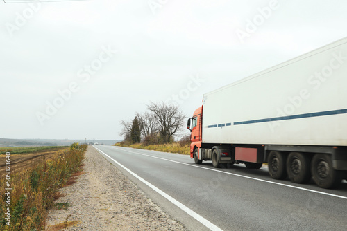 Truck rides on asphalt road in autumn
