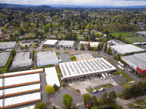 Shooting from a drone. Cozy green town, mountains. Central street with industrial buildings, car parking. Ecologically clean place, construction, housing. Planning, topography.