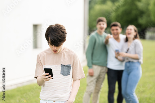 Teenager boy looking at phone and suffering cyber bullying. photo
