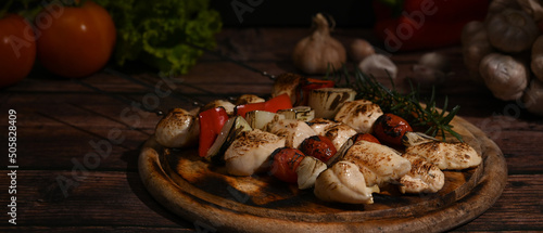 Shish kebab with cherry tomato and sweet pepper and onions on wooden plate. Barbecue, food, holiday concept © Prathankarnpap