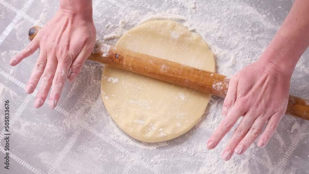 Apple pie preparation series - woman rolling out dough with pin on a table Apple pie preparation series - woman rolling out dough with pin on a table