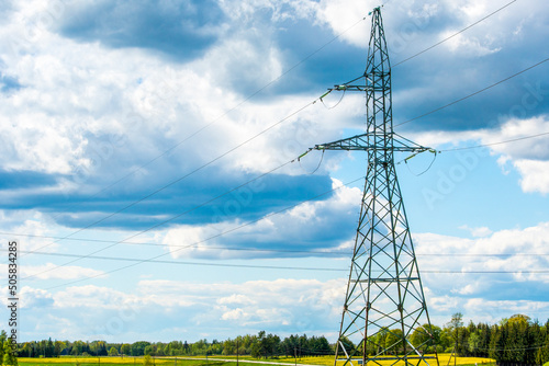 Fototapeta Power transmission lines and tall electricity pylon against the blue sky in the