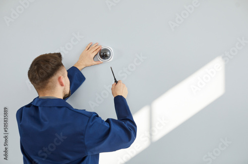 Foto Male technician installing surveillance camera on light copy space wall
