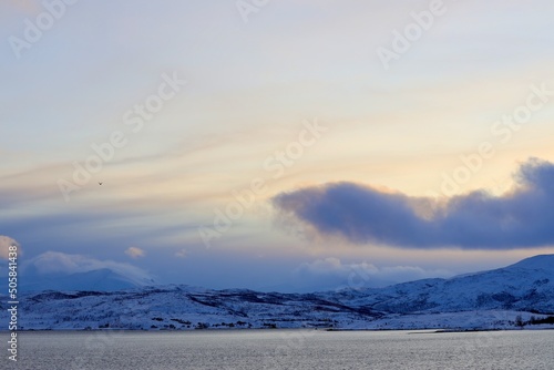 sunrise in the mountains with snow in a fjord by tromso norway