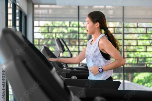 young happy asian woman athlete run on treadmill, running machine, in indoor gym fitness for health;