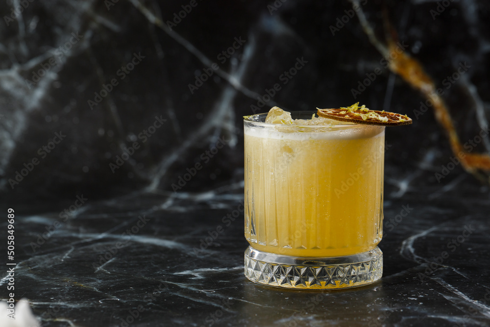 Fruit mixology with mezcal and dry lime on black marble background. Warm colored cocktails. Mezcal cocktail.