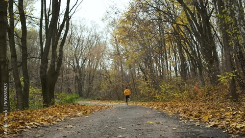 A young brutal man trains in an autumn park to compete. 100 meters. Sports and discipline. Frame behind