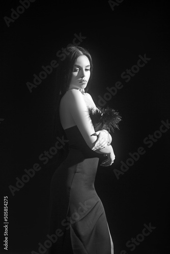 Fashion studio portrait of young beautiful female model in black sexy dress. Glamour photo of pretty girl with slim figure.