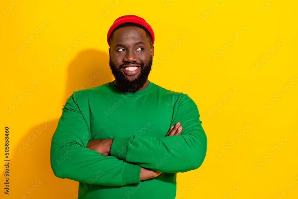 Photo of positive creative guy look empty space folded hands wear red beanie green shirt isolated yellow color background Photo of positive creative guy look empty space folded hands wear red beanie green shirt isolated yellow color background