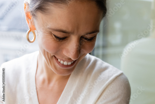 close up portrait of woman in ring earring smiling at home on blurred background