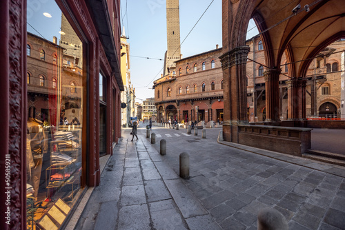 Street view of the old town with famous galleries and Asinelli towers on Ravegnana square in Bologna city. Traveling Italy concept photo