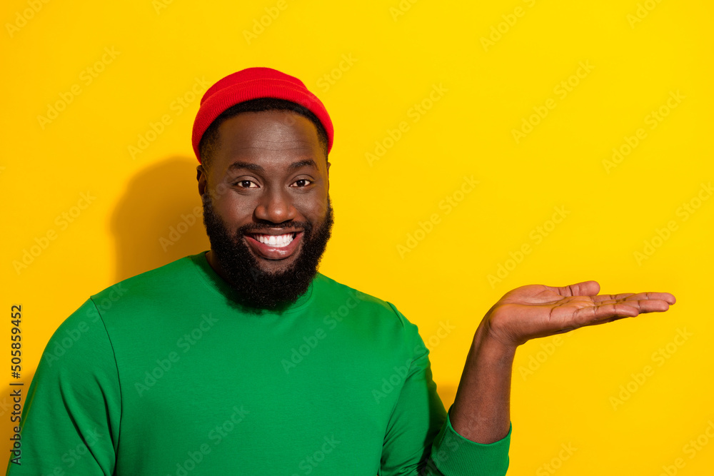 Portrait of attractive cheerful guy holding on palm copy blank space ad isolated over bright yellow color background Portrait of attractive cheerful guy holding on palm copy blank space ad isolated over bright yellow color background