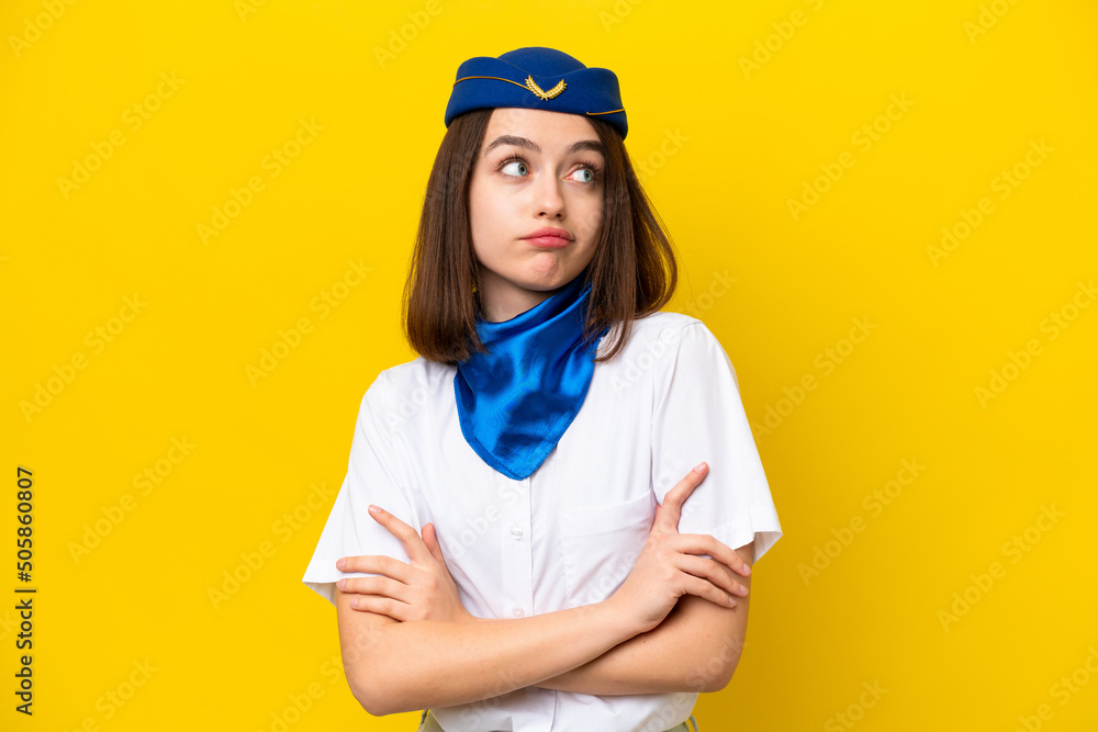 Airplane stewardess Ukrainian woman isolated on yellow background making doubts gesture while lifting the shoulders Airplane stewardess Ukrainian woman isolated on yellow background making doubts gesture while lifting the shoulders