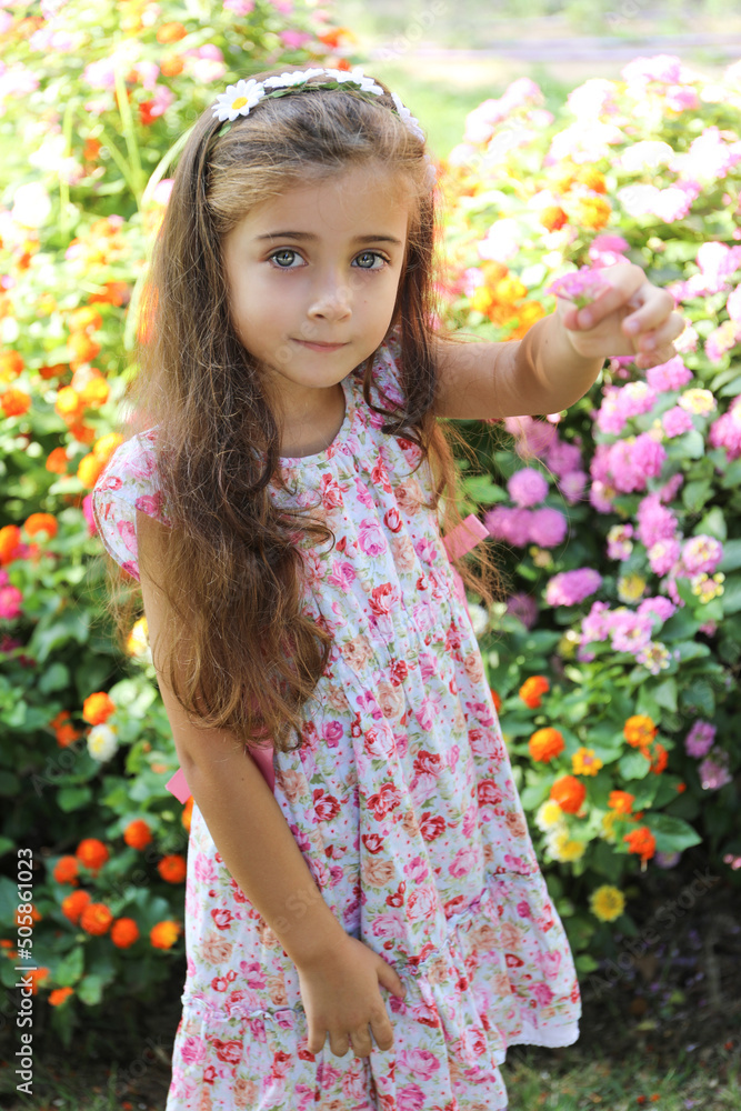 a pretty girl with brown hair and light green eyes, wearing a flowery dress, happy and smiling holding two flowers in the city of Alicante a pretty girl with brown hair and light green eyes, wearing a flowery dress, happy and smiling holding two flowers in the city of Alicante