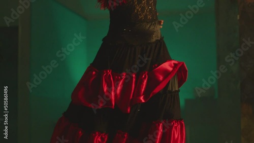 Woman dancing spanish hot dance . Professional dancer in latin dress performs dance movement by skirt . Closeup studio shot of female artist dancing inside dark place . Concept footage of dance art