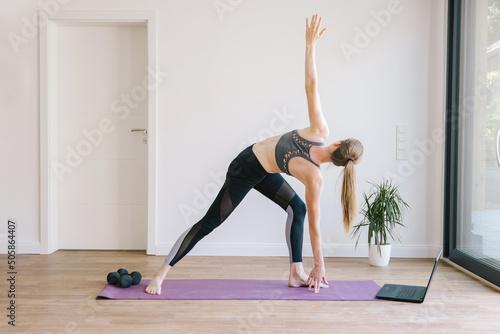 Young woman practices yoga class at home. Girl athlete goes in for sports or Pilates. Assanas, yoga poses for beginners