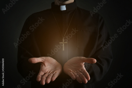Fototapeta Priest reaching out his hands with holy light on dark background, closeup