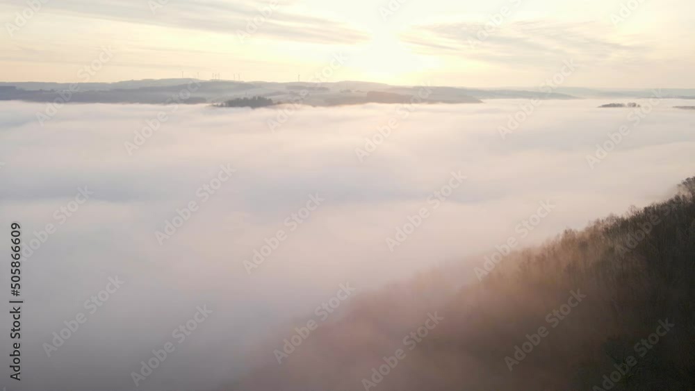 Beautiful and thick morning fog flowing through a vast valley during winter in Europe. Upwards camera tilt revealing a stunning sunrise Beautiful and thick morning fog flowing through a vast valley during winter in Europe. Upwards camera tilt revealing a stunning sunrise