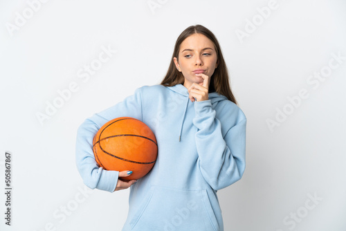 Young Lithuanian woman playing basketball isolated on white background having doubts while looking up