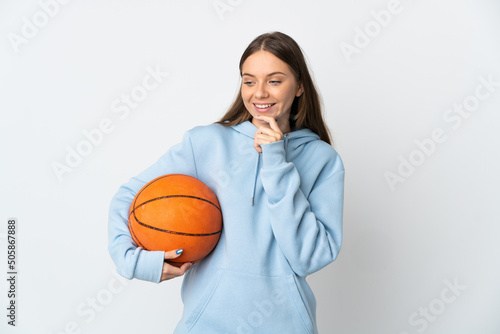 Young Lithuanian woman playing basketball isolated on white background looking to the side and smiling