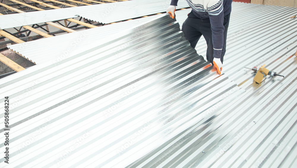 Φωτογραφία Worker puts the metal tiles on the roof of a house.
