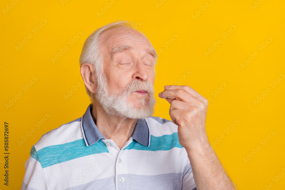 Portrait of attractive funny dreamy cheerful grey haired man tasting invisible food isolated over bright yellow color background Portrait of attractive funny dreamy cheerful grey haired man tasting invisible food isolated over bright yellow color background
