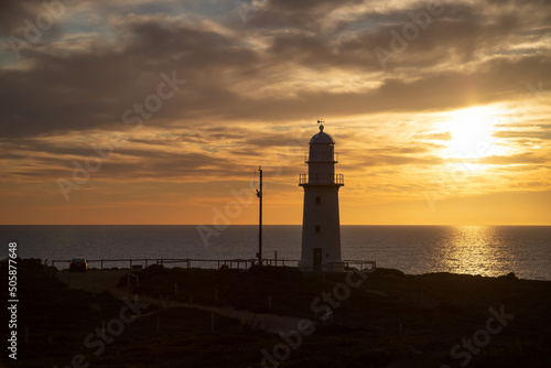 Lighthouse silhouette against the backdrop of the ocean and sunset, blue evening sky and clouds, landscape