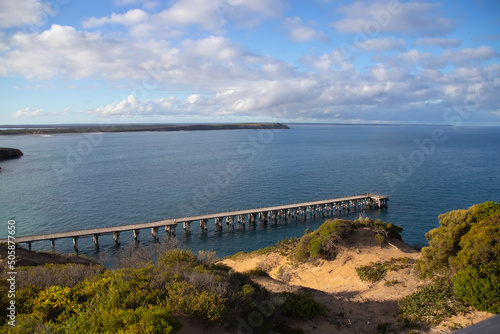 Landscape with a seacoast, long jetty and ocean, on blue sky and clouds background 