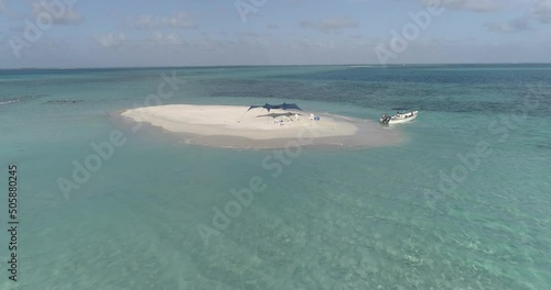 Aerial aproach over Sandbar caribbean Island, motorboat and tent without people. teal sea photo