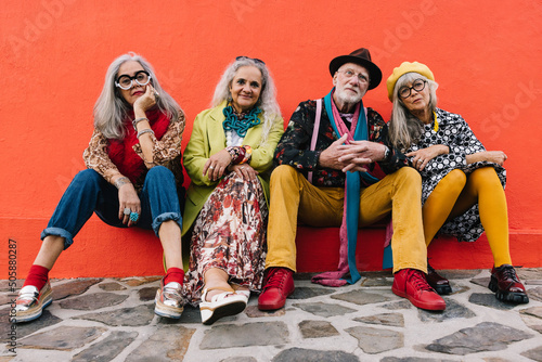 Carefree elderly friends sitting against a red wall