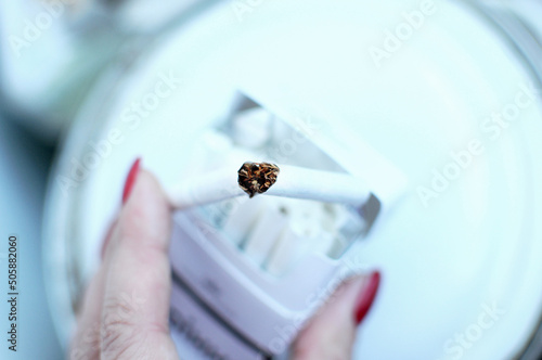 Broken cigarette and a pack of cigarette in female hand. Quit Smoking Concept.