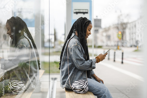 Young woman waiting for a bus at a bus stop
