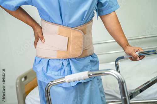 Asian lady patient wearing back pain support belt for orthopedic lumbar with walker.