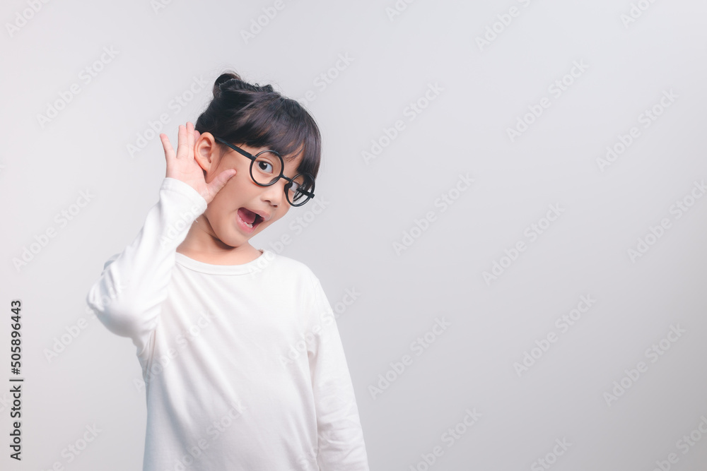 Little Asian girl holds her hand near her ear and listenings. Disability day.Deaf kid. Exciting face on Asian child girl. Turn off the phone and listen to your child. Little Asian girl holds her hand near her ear and listenings. Disability day.Deaf kid. Exciting face on Asian child girl. Turn off the phone and listen to your child.